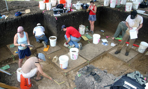 group of students digging excavation site