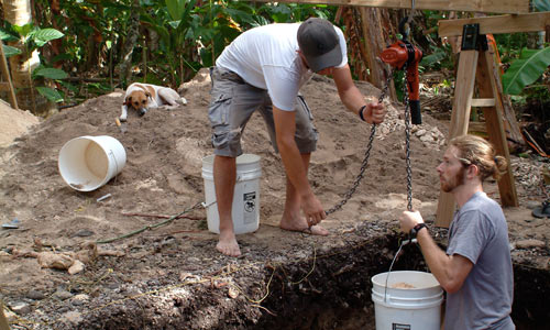 two men dig dirt out of jungle hole