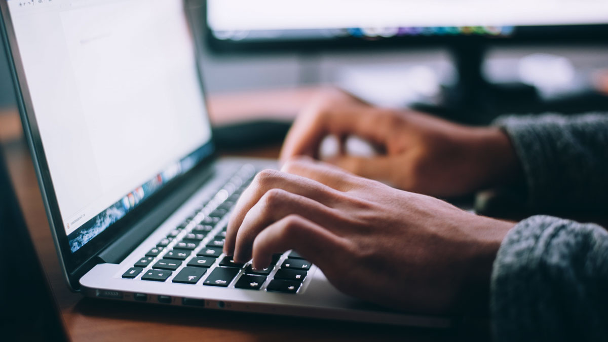 Hands typing notes on a laptop