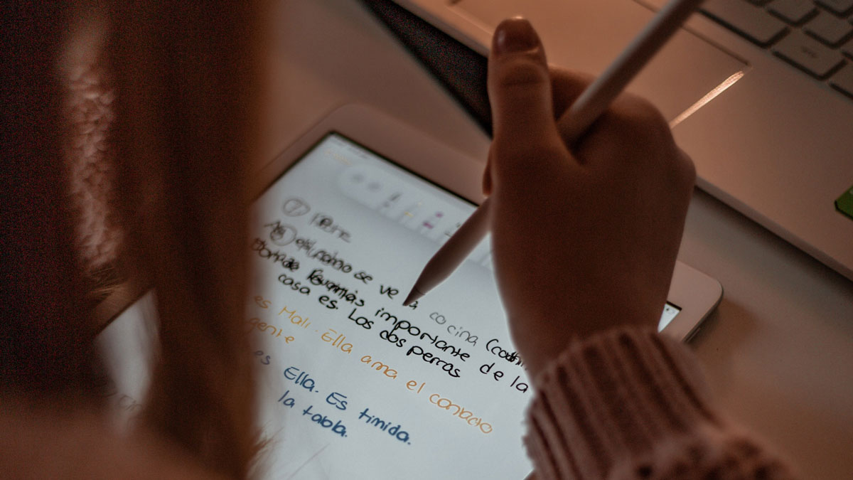 A students takes notes on their tablet with a stylus pen