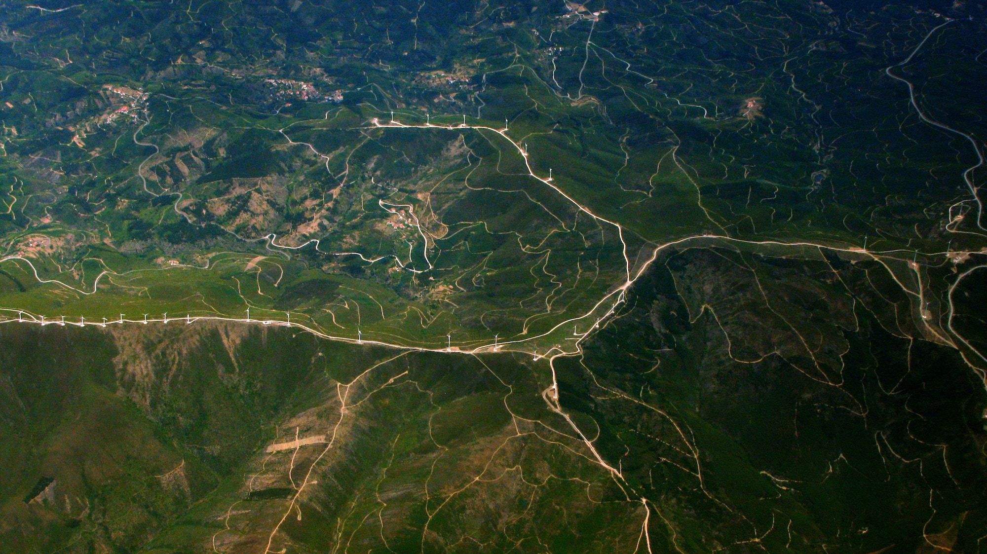 Aerial view of land with a large group of windmills visible