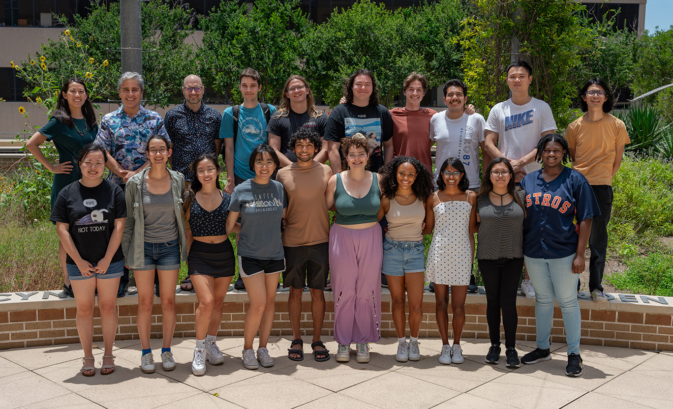 group photo of 20 people of mixed demogaphics standing in two rows in front of trees