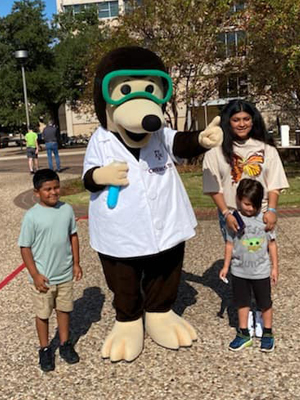 The Chemistry mole poses with three children at the 2022 Texas A&M Chemistry Open House