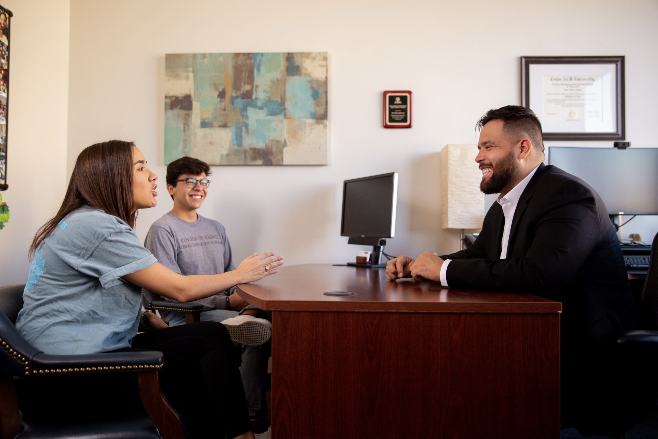Texas A&M Science Leadership Scholars Program academic advisor Victor Castillo visits with two students in his office within the John R. Blocker Building