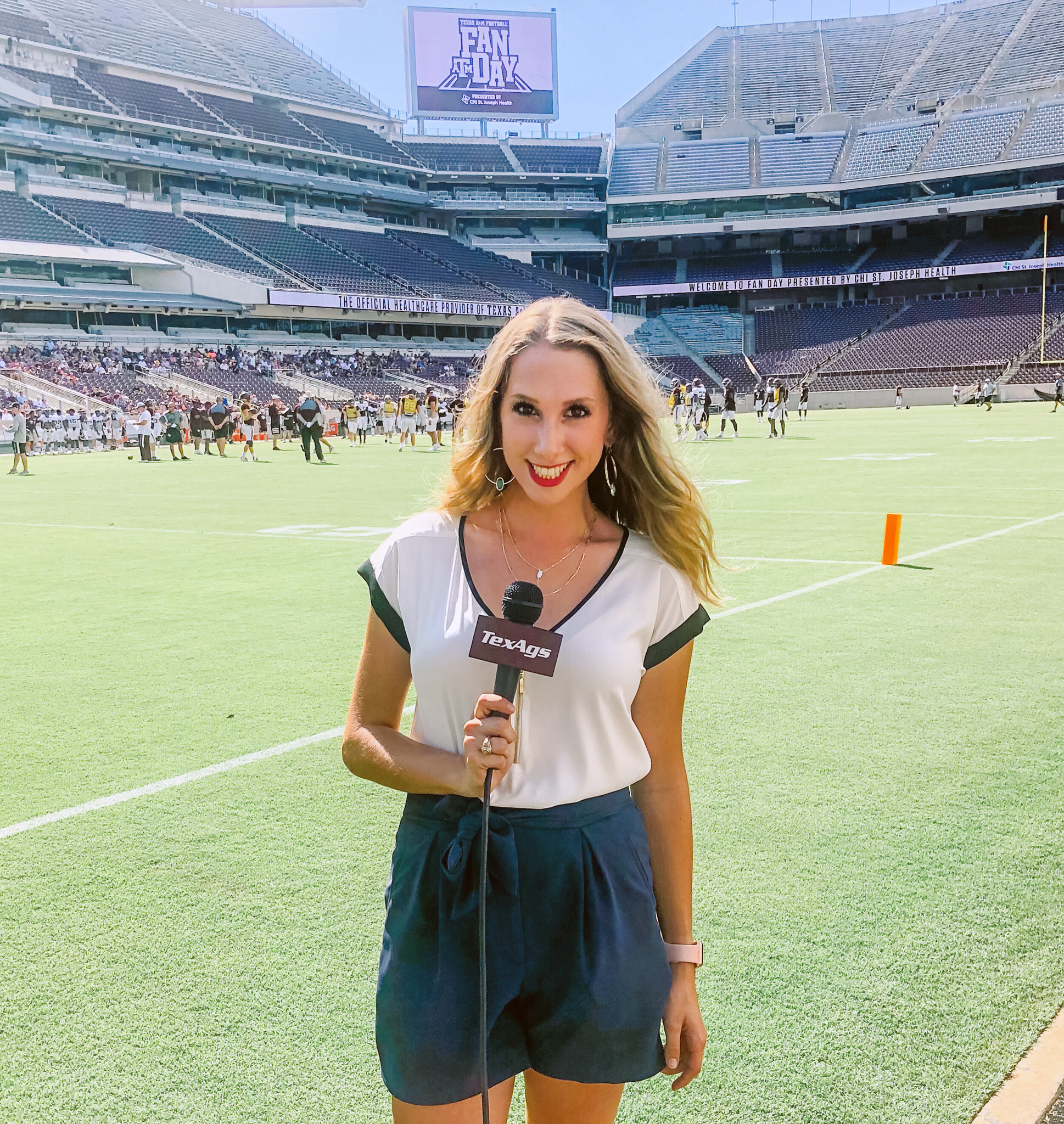 2019 Texas A&M telecommunications graduate Lia Musgrave holds a TexAgs microphone while reporting from the sidelines of Kyle Field at Texas A&M Football Fan Day