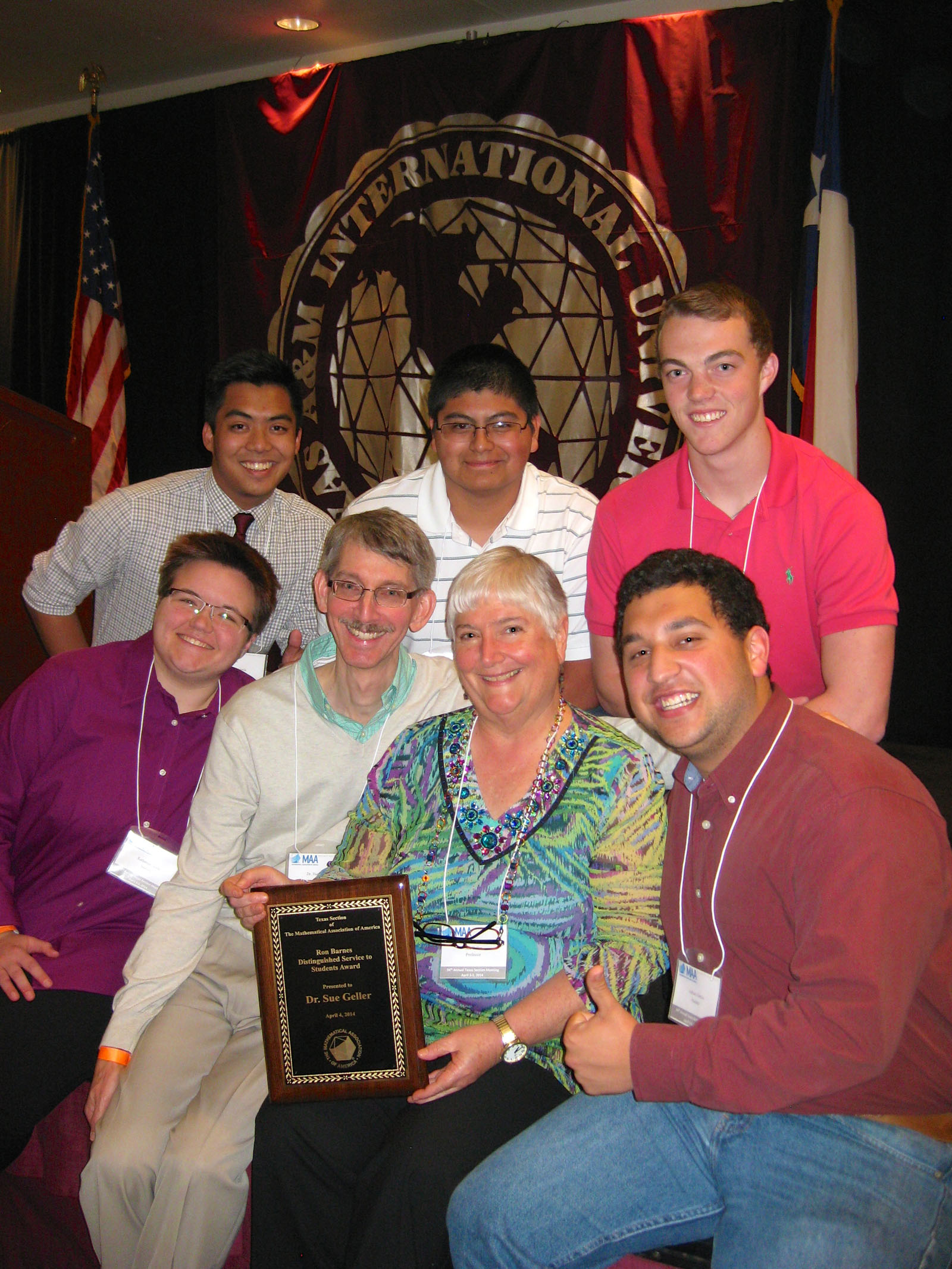Texas A&M mathematician Sue Geller holds a plaque surrounded by fellow faculty and her math students