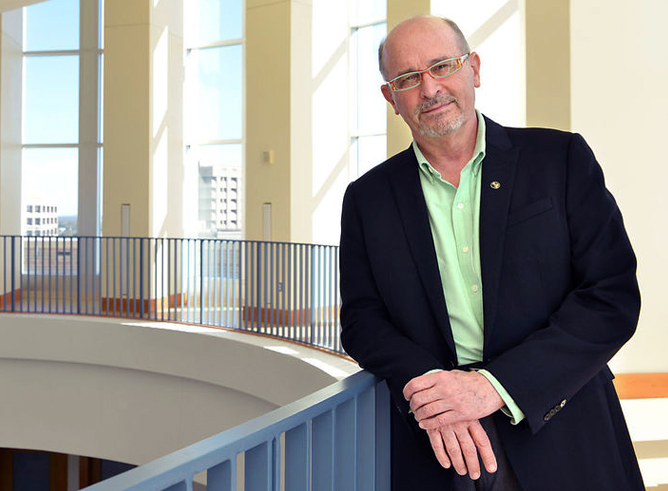Portrait of Texas A&M astronomer Nicholas Suntzeff leaning against a balcony within the Mitchell Institute on the Texas A&M campus