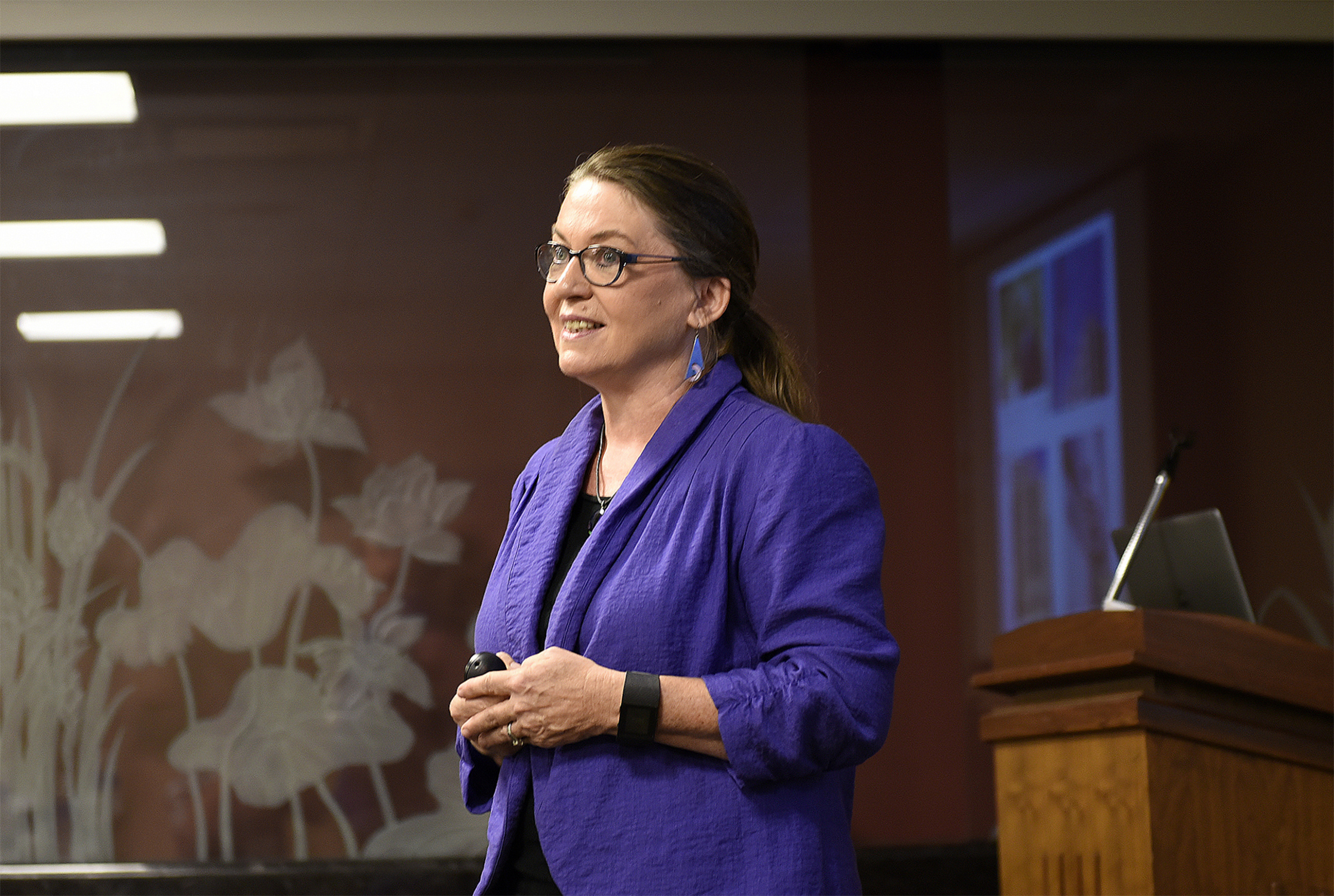 Texas A&M biologist Deborah Bell Pedersen stands in front of a podium and speaks to an audience