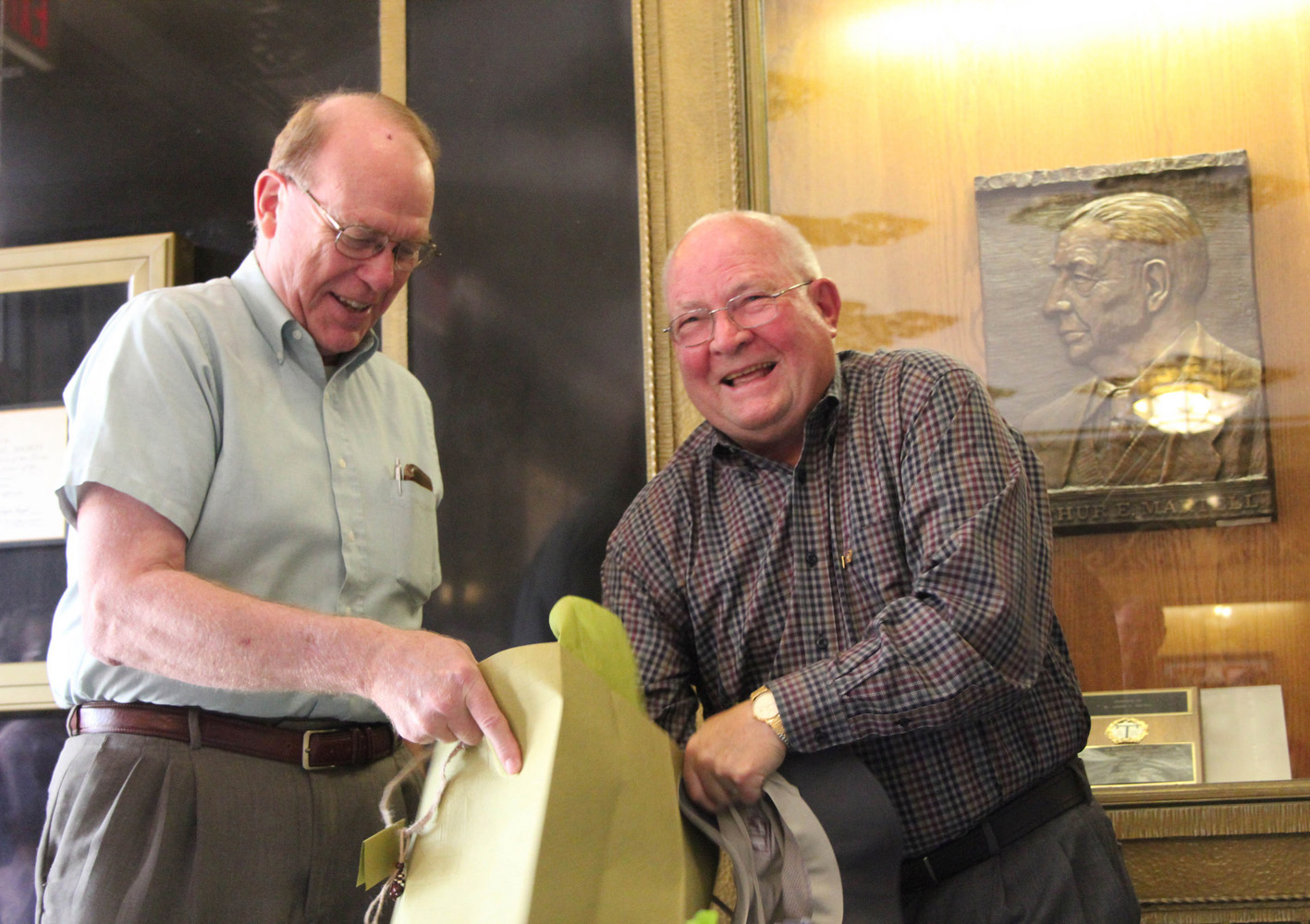 Texas A&M chemist Michael Rosynek (left) looks on as fellow Texas A&M chemist John Fackler (right) opens a gift at his 80th birthday celebration in the Texas A&M Chemistry Building.
