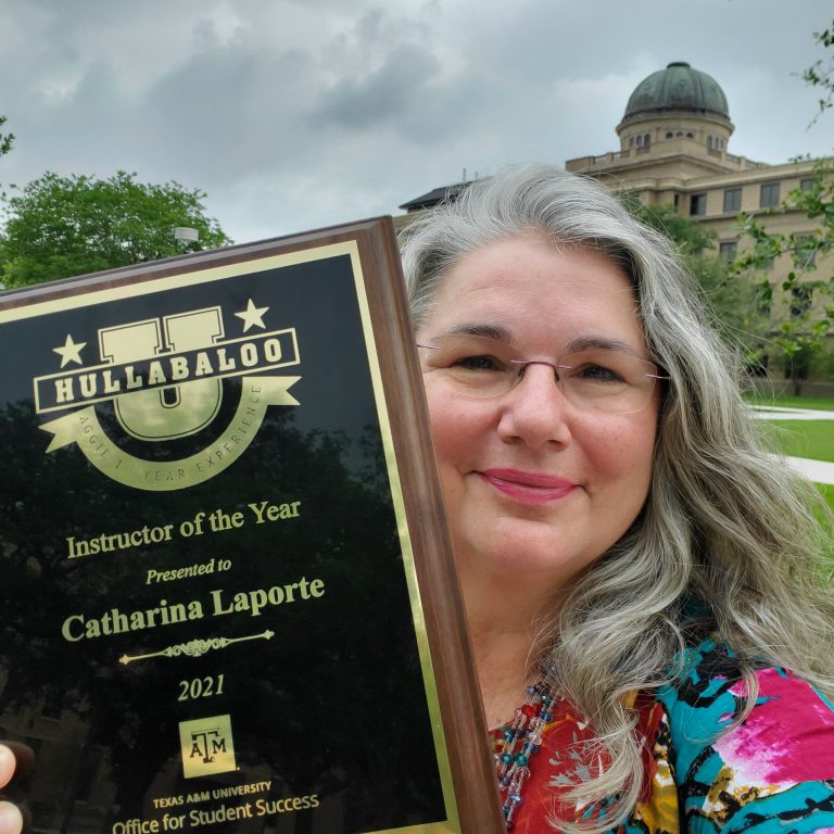 Texas A&M anthropologist Catharina Laporte poses with her Hullabaloo U Instructor of the Year award plaque with the Academic Building in the background