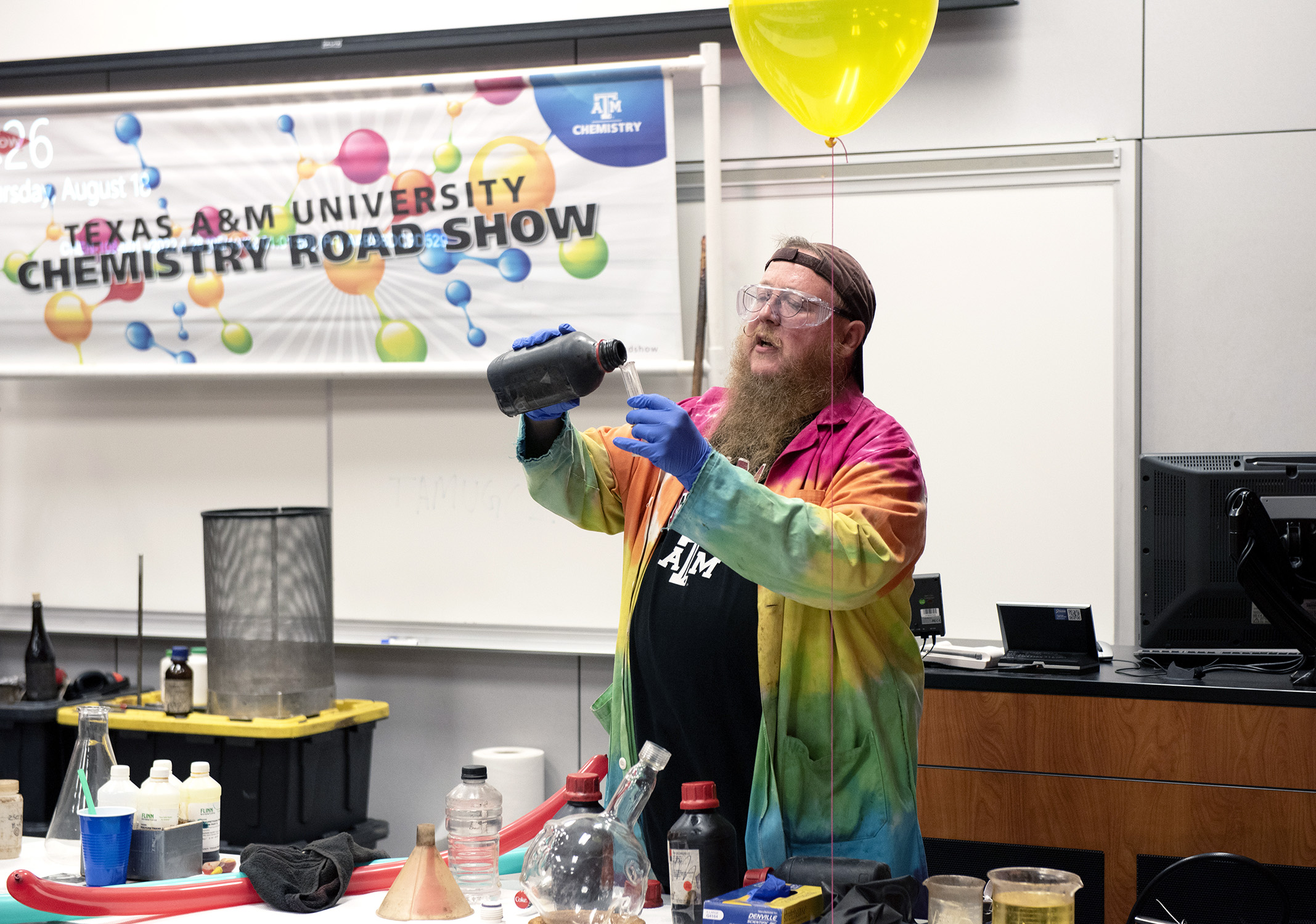 Texas A&M chemist James Pennington pours a solution into a cylinder during the Chemistry Road Show