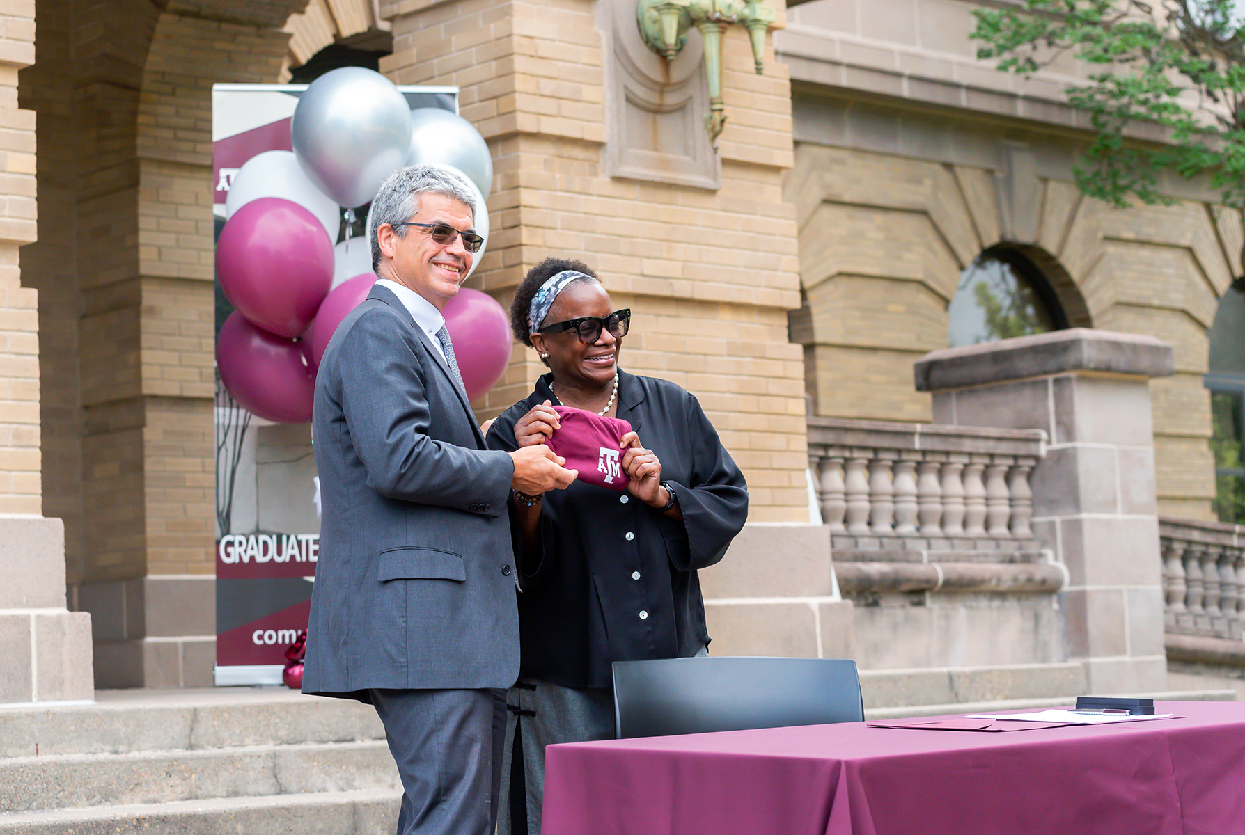 College of Arts and Sciences Interim Dean Dr. José Luis Bermúdez presents Dr. Kathleen McElroy with a Texas A&M t-shirt during a signing ceremony outside the Academic Building unveiling her as director of the Texas A&M Journalism Program