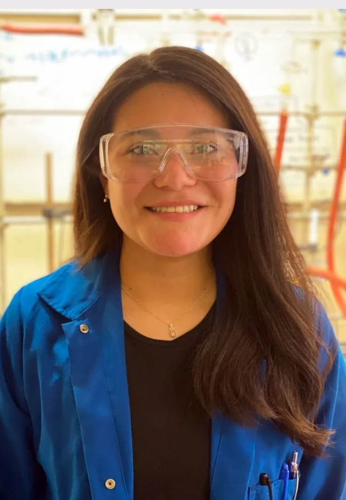 Texas A&M chemistry graduate student Jeanette Piña, wearing clear goggles and a blue lab coat within the Thomas Lab