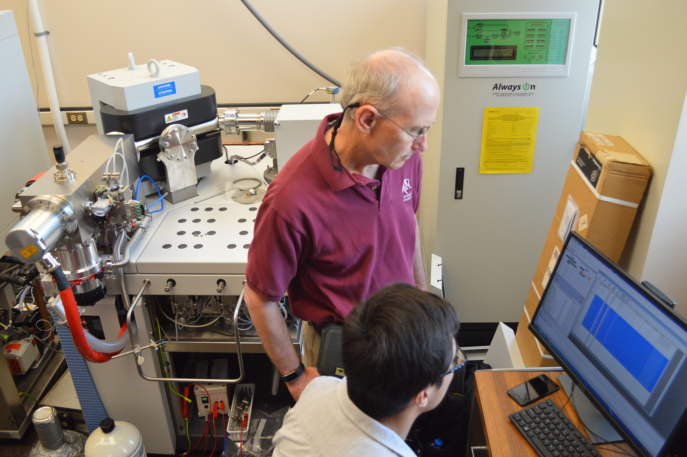Texas A&M geologist Ethan Grossman (standing) and Texas A&M geology Ph.D. candidate Zeyang Sun (sitting), working in the Stable Isotope Geosciences Facility