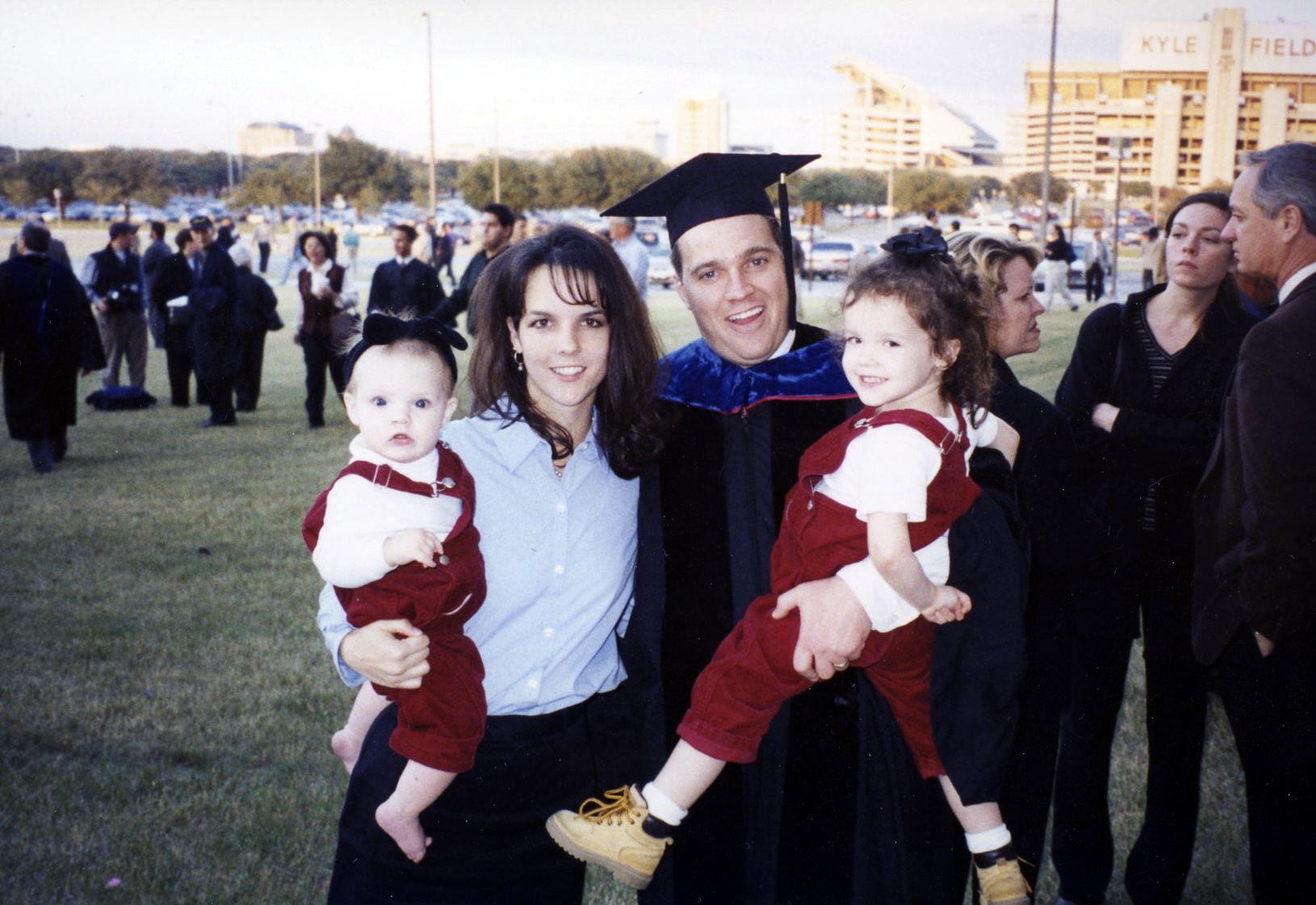 C. Shane Reese stands outside Reed Arena in his cap and gown, celebrating his 1999 graduation from Texas A&M University with his wife and daughters
