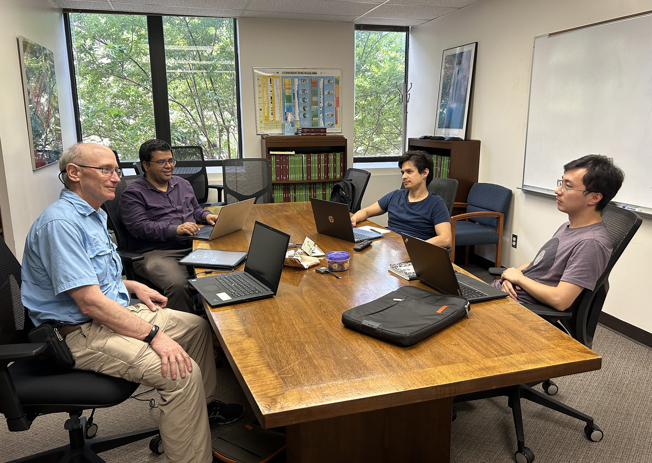 Texas A&M scientists Dr. Ethan Grossman, Dr. Sarbajit Banerjee, Dr. Saul Perez-Beltran and Zeyang Sun sit at a conference table, discussing next steps in their research