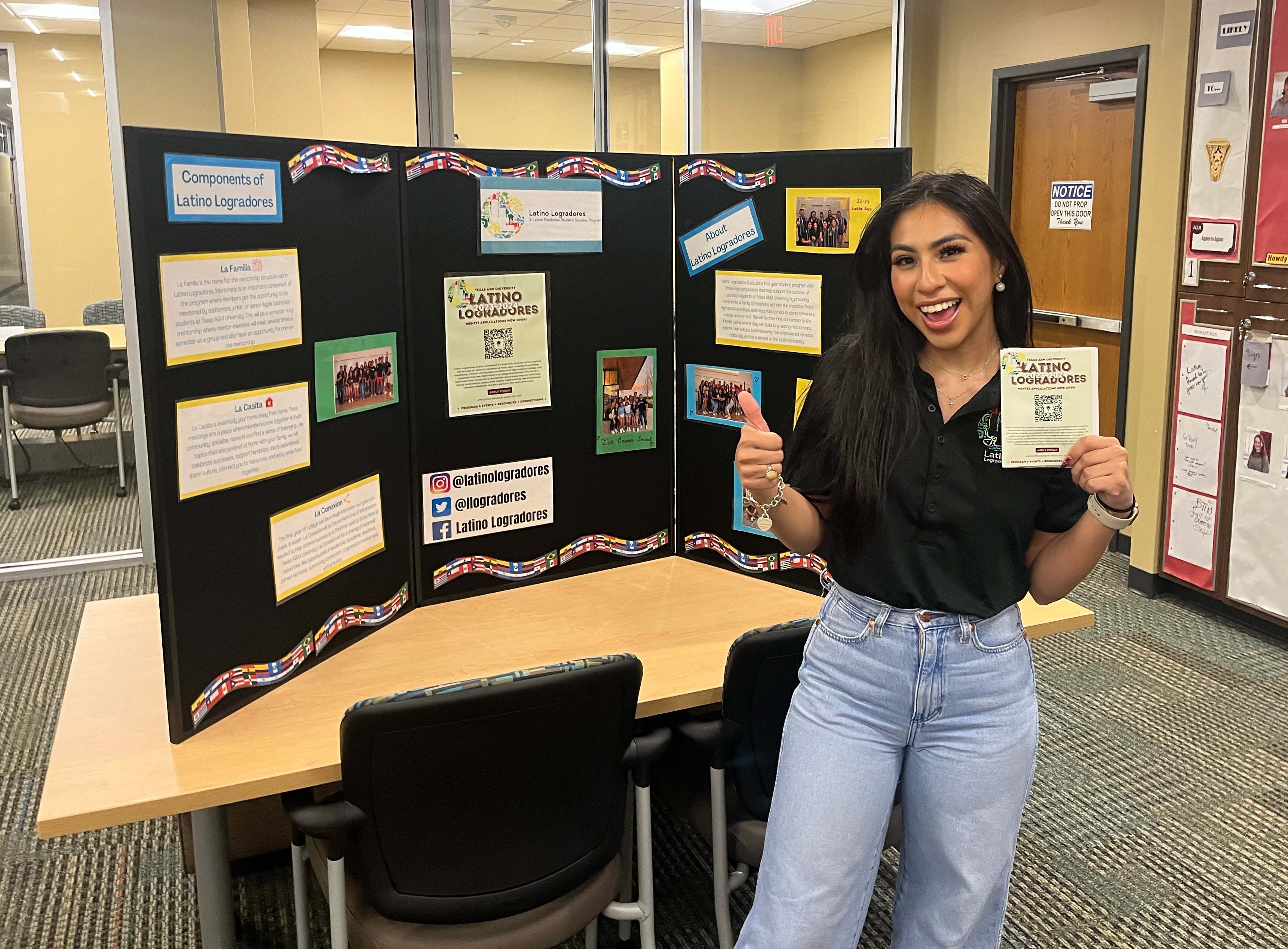 Texas A&M women's and gender studies major Odyssey Olmos, standing by an exhibit for Latino Logradores in the Student Programs Office within the Memorial Student Center