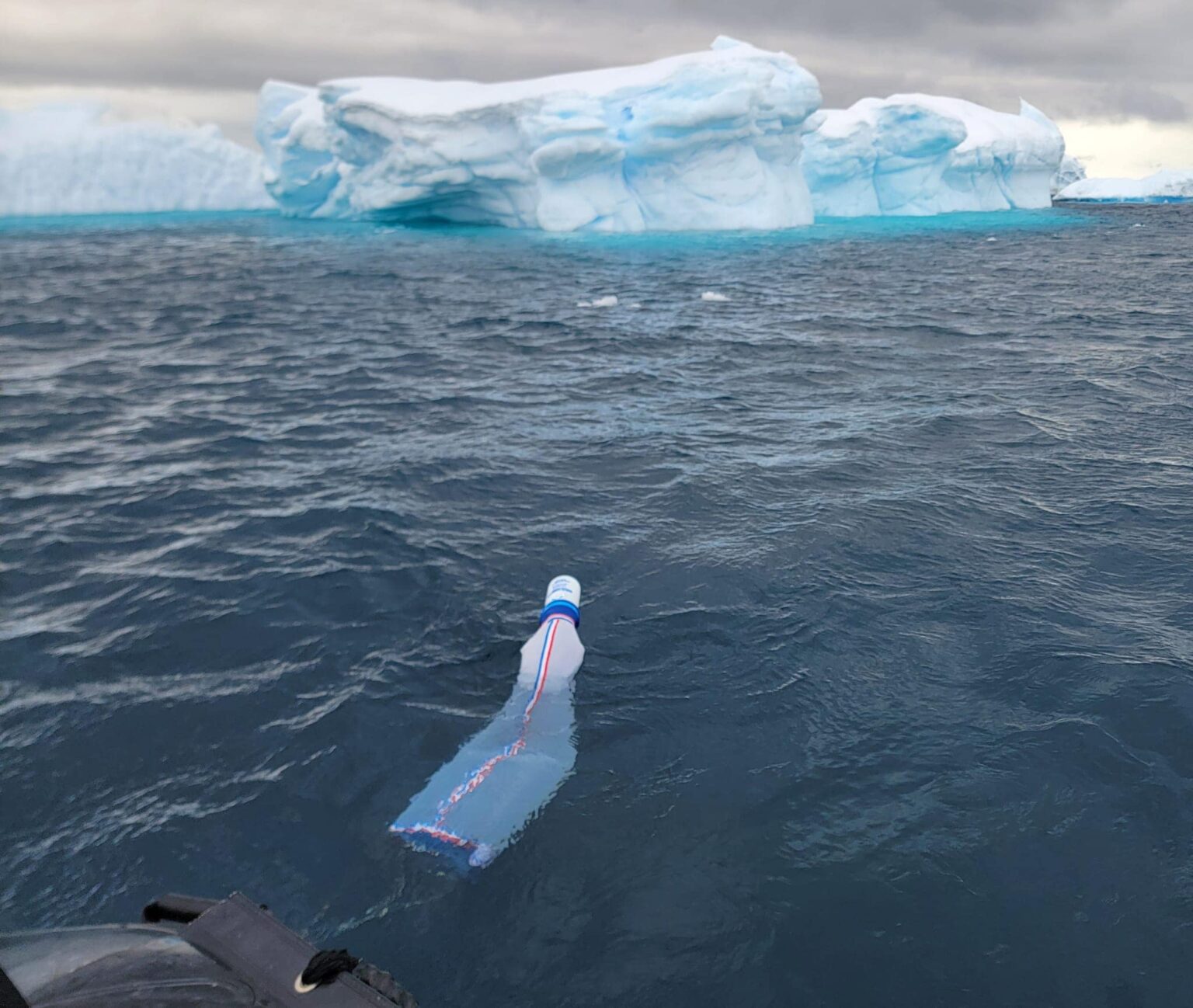 A bag collecting water samples floats while filling amid choppy seas with an iceberg in the background during Texas A&M University's first study abroad trip to Antarctica in late fall 2023