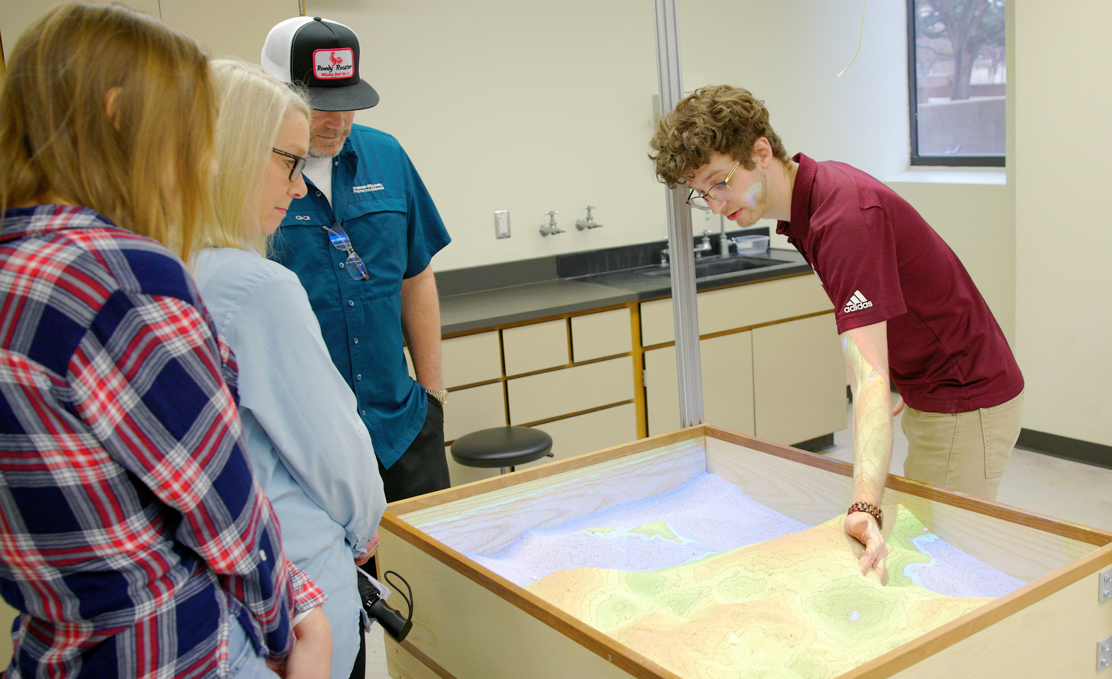 Texas A&M University Geology and Geophysics graduate student Dirk van de Laar uses a sand table to illustrate a geological concept on Aggieland Saturday, held February 10, 2024