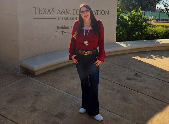 1990 Texas A&M University English graduate Susan Smallman, standing in front of the Texas A&M Foundation sign on the Texas A&M campus