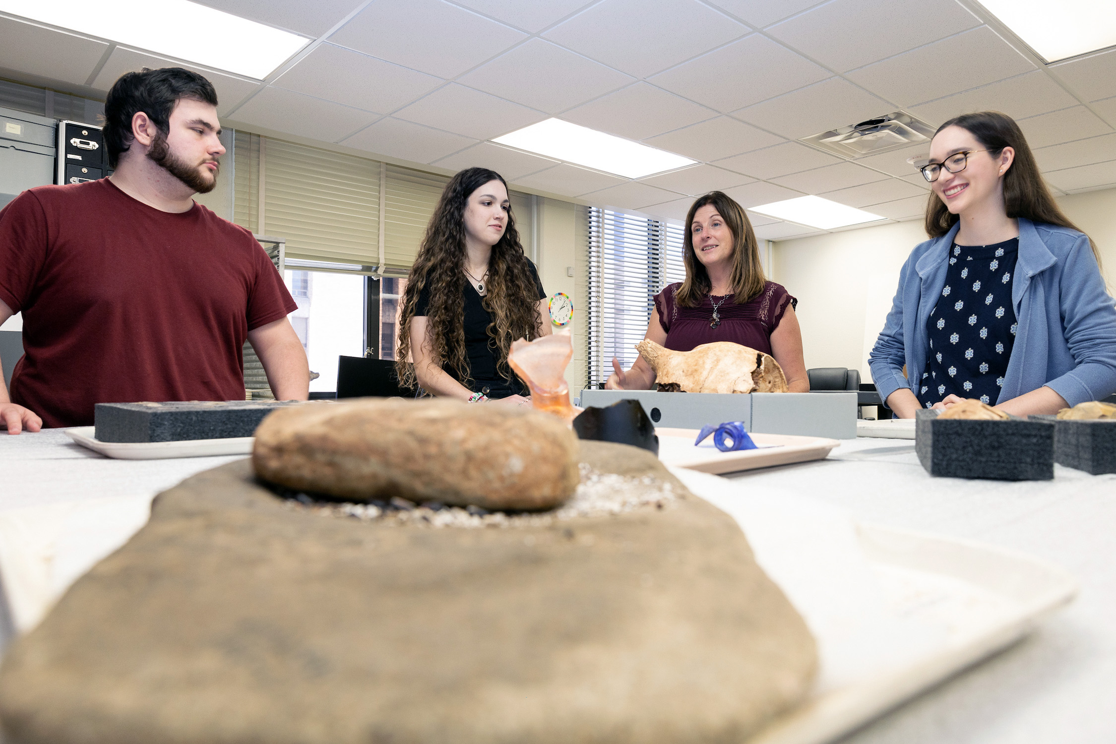 Dr. Katie Custer Bojakowski and other staff within Texas A&M University's Anthropology Research Collections discuss an item within the collection at a table in the laboratory