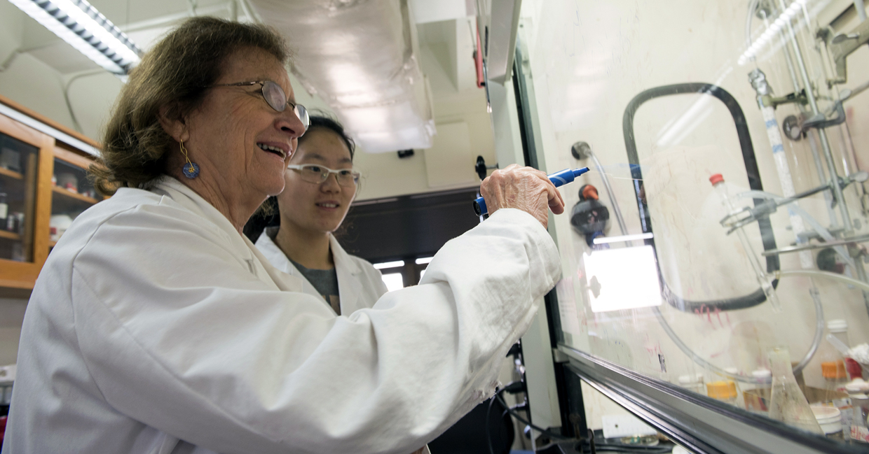 Texas A&M University chemist Marcetta Darensbourg instructs a student in her lab wearing safety goggles and a white lab coat