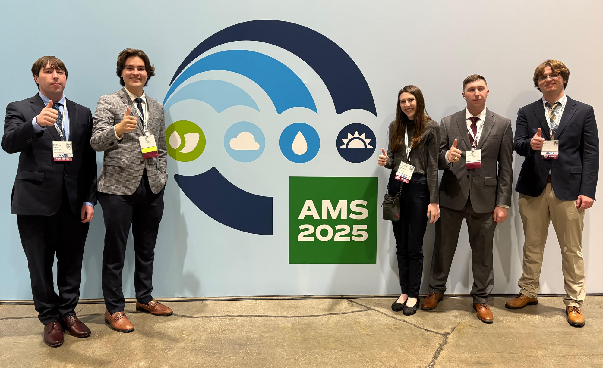 Five individuals posing with thumbs up in front of an AMS 2025 conference banner.