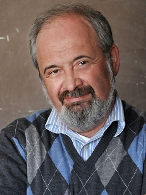 Portrait of Dr. Peter Kuchment smiling at the camera, wearing a sweater vest over a collared shirt.