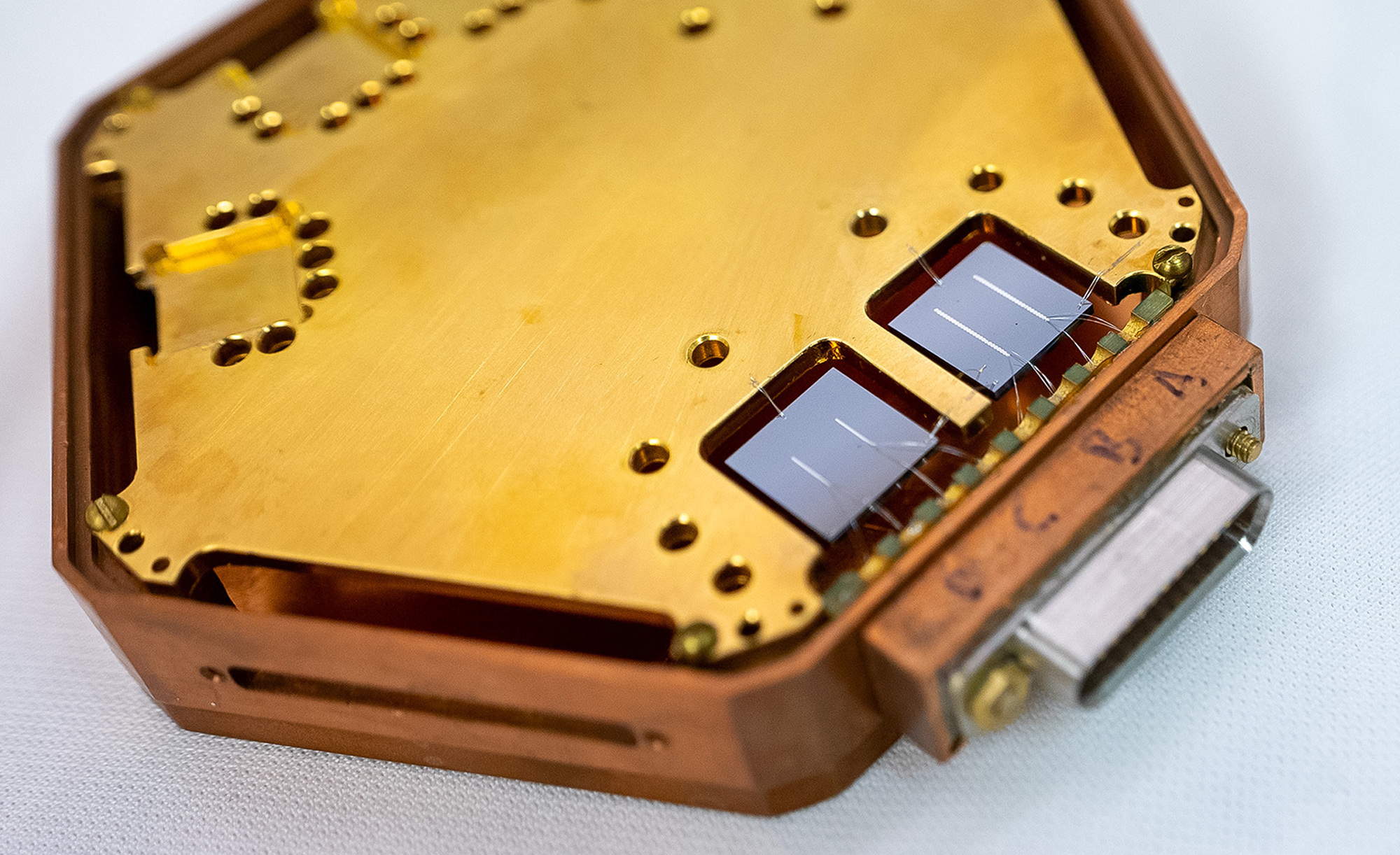 Close-up of a hexagonal structure holding two square chips, each with two reflective lines.