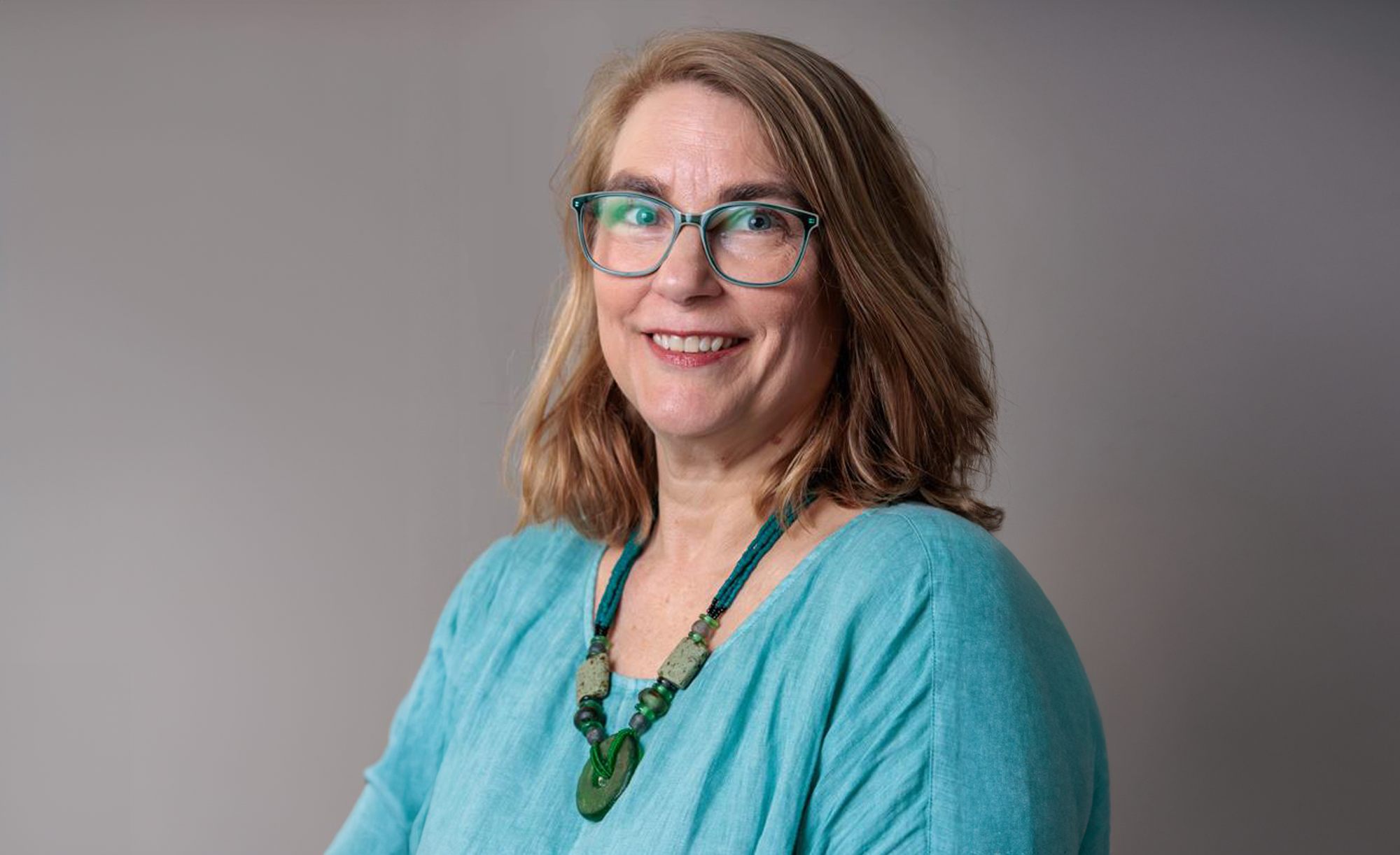 Headshot of Dr. Glanville wearing a light blue top in front of a grey back drop.