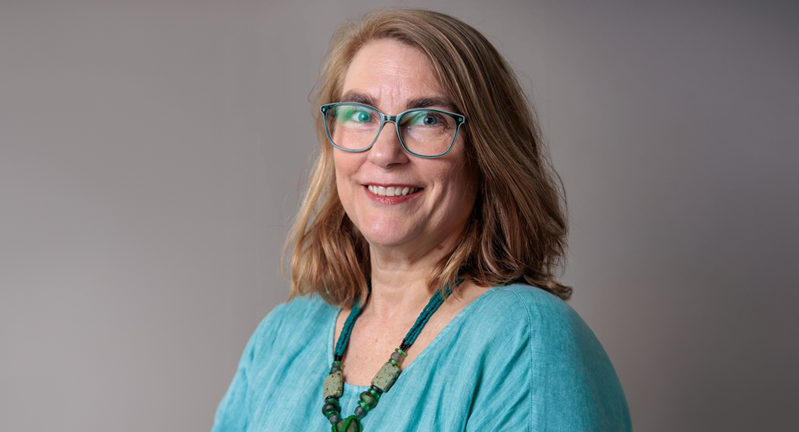 Headshot of Dr. Glanville wearing a light blue top in front of a grey back drop.