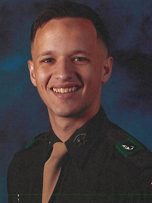 Jackson smiles in front of blue backdrop, wearing Corps of Cadets uniform.