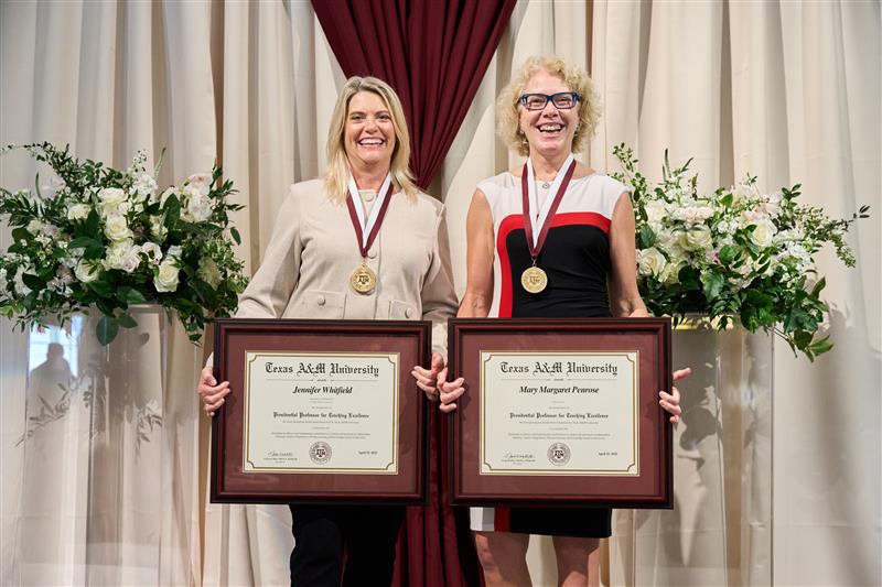 Dr. Jen Whitfield holding her award and wearing her medal, next to the other award-winner, Mary Margaret Penrose from the School of Law.