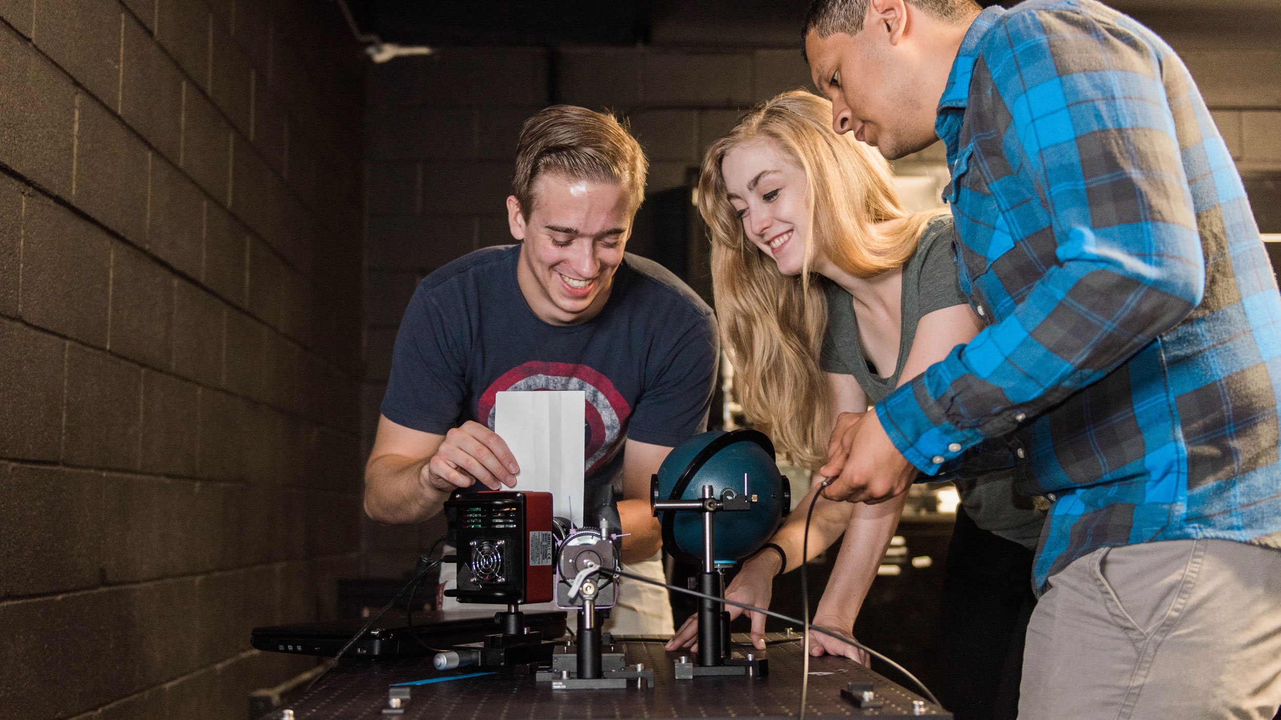 Three students working with physics equipment.